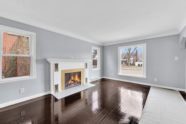 unfurnished living room featuring visible vents, a premium fireplace, baseboards, and hardwood / wood-style floors