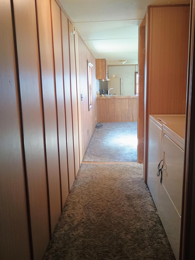 hallway featuring carpet floors, independent washer and dryer, and wooden walls