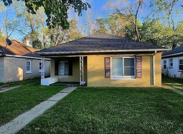 view of front of home featuring concrete block siding, a front lawn, and roof with shingles