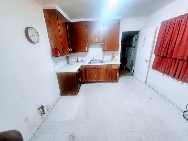 kitchen with brown cabinetry, light floors, light countertops, and a sink