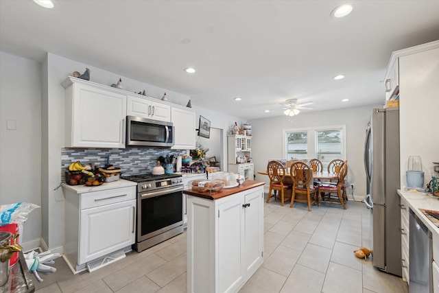 kitchen with recessed lighting, a ceiling fan, white cabinets, appliances with stainless steel finishes, and backsplash