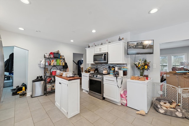 kitchen featuring recessed lighting, butcher block counters, backsplash, appliances with stainless steel finishes, and white cabinetry