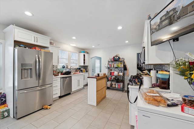 kitchen with stainless steel appliances, wooden counters, backsplash, white cabinets, and a sink