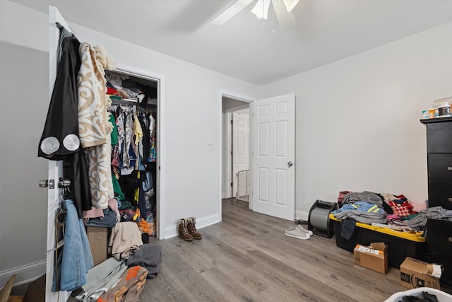 bedroom featuring a ceiling fan, a closet, baseboards, and wood finished floors