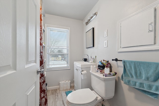 bathroom with toilet, baseboards, and vanity