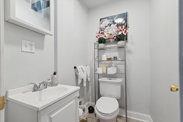 bathroom with toilet, baseboards, and vanity