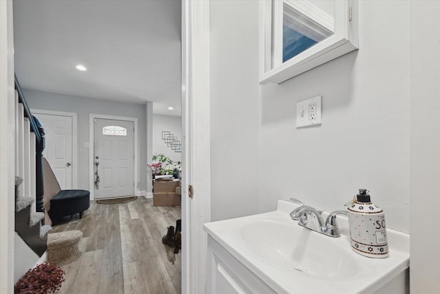 bathroom featuring recessed lighting, a sink, and wood finished floors