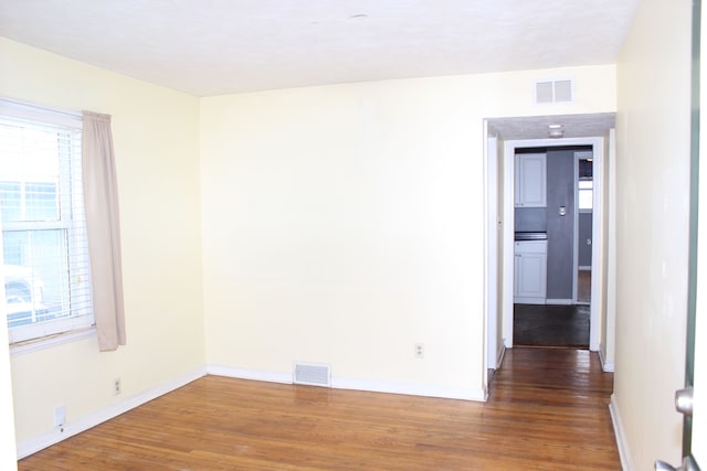 empty room featuring visible vents, baseboards, and wood finished floors