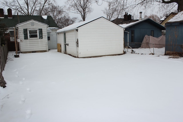 snowy yard with fence and an outbuilding