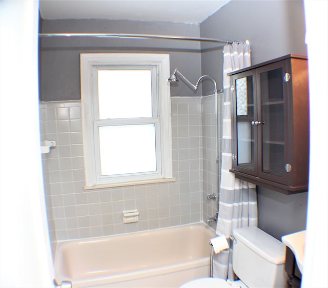 bathroom with shower / bath combination with curtain and toilet