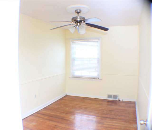 unfurnished room with a ceiling fan, baseboards, visible vents, and wood finished floors