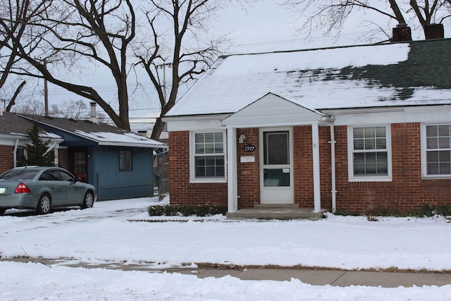 bungalow-style house featuring a chimney and brick siding