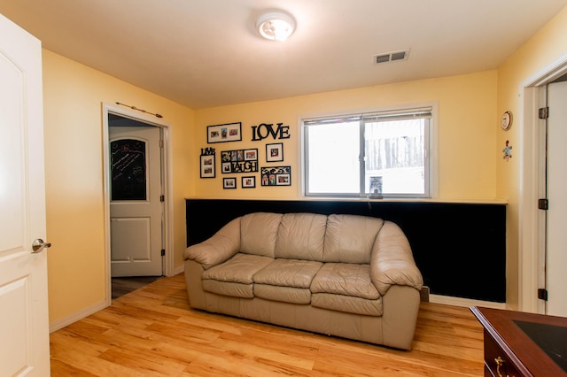 living room featuring light wood-style flooring, visible vents, and baseboards