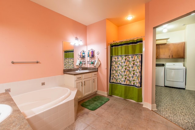 full bathroom with a garden tub, vanity, washer and dryer, baseboards, and tile patterned floors