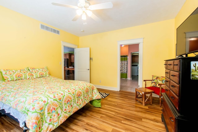 bedroom featuring ceiling fan, light wood-style flooring, visible vents, and baseboards