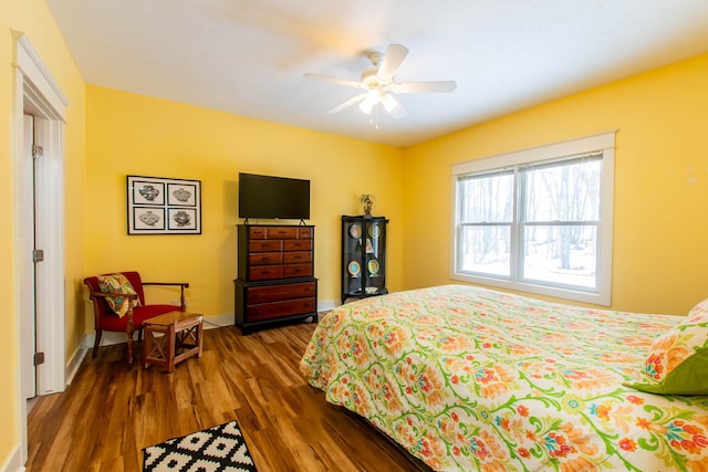 bedroom with dark wood-style flooring, a ceiling fan, and baseboards