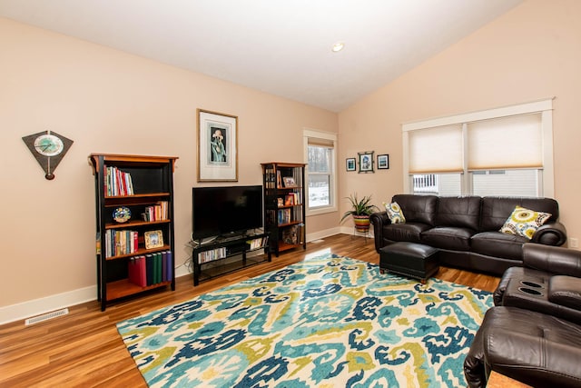 living area featuring lofted ceiling, baseboards, visible vents, and wood finished floors