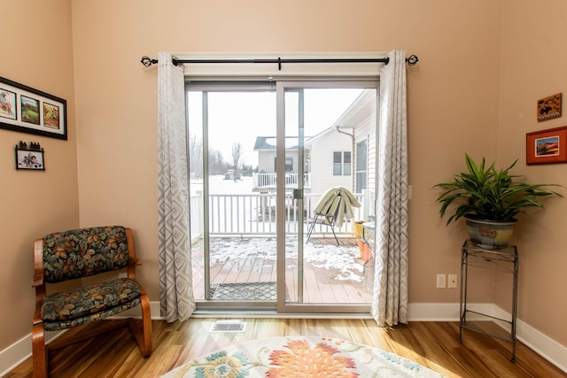 doorway to outside featuring wood finished floors, visible vents, and baseboards