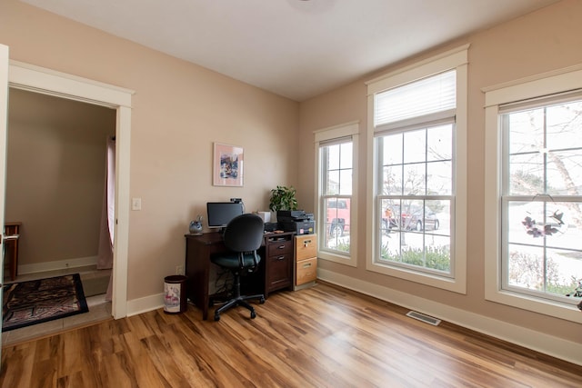 office space with light wood finished floors, visible vents, and baseboards