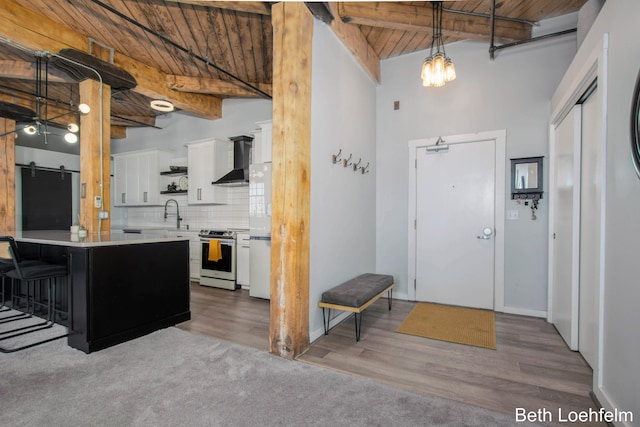 kitchen with white cabinets, wooden ceiling, wall chimney exhaust hood, stainless steel range with electric stovetop, and backsplash