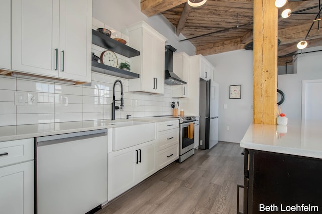 kitchen featuring wood finished floors, light countertops, appliances with stainless steel finishes, wall chimney range hood, and open shelves