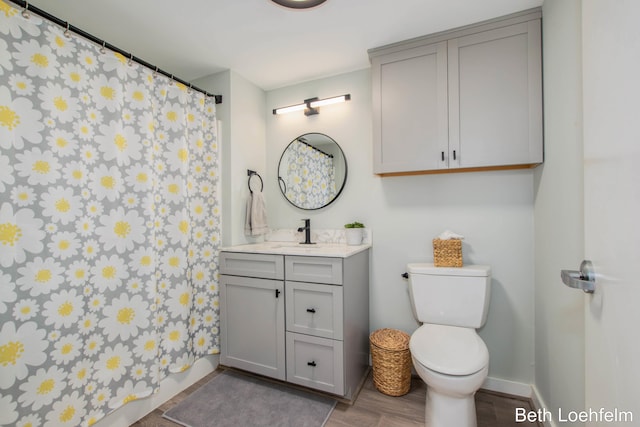 full bath with baseboards, a shower with shower curtain, toilet, wood finished floors, and vanity