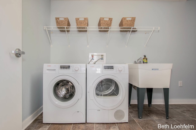 clothes washing area featuring laundry area, washing machine and dryer, baseboards, and a sink