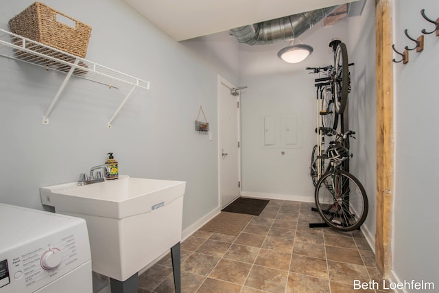 laundry area with laundry area, a sink, washer / dryer, and baseboards