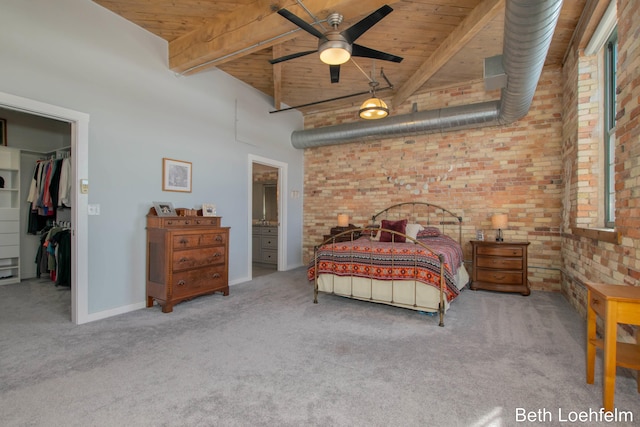 carpeted bedroom featuring a walk in closet, wood ceiling, beamed ceiling, and brick wall