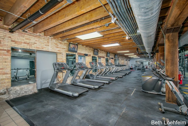 exercise room featuring brick wall