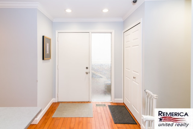 entrance foyer with ornamental molding, light wood-type flooring, and baseboards