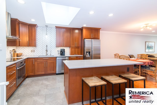 kitchen featuring decorative backsplash, a kitchen breakfast bar, stainless steel appliances, wall chimney range hood, and a sink