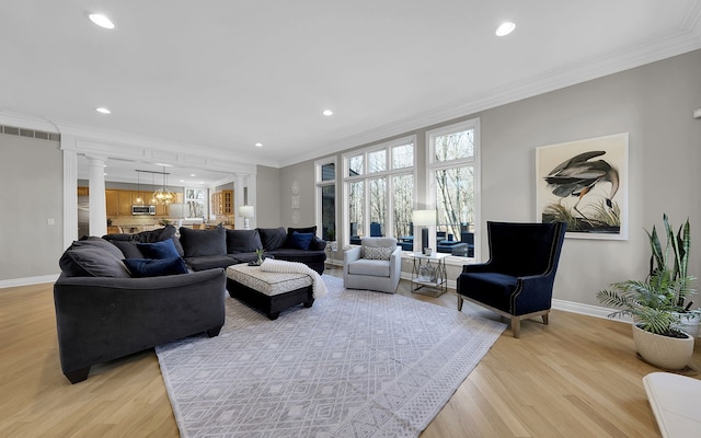 living area featuring crown molding, decorative columns, visible vents, and light wood-type flooring