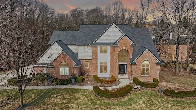 traditional-style home featuring brick siding, a chimney, and a shingled roof