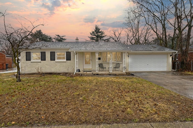 ranch-style home featuring brick siding, a porch, a lawn, an attached garage, and driveway