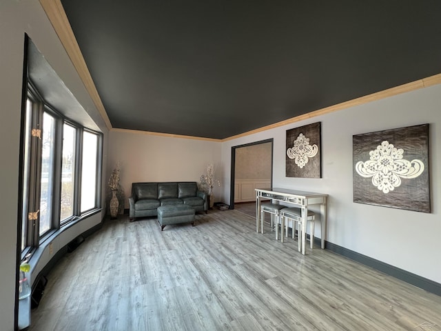 living area featuring baseboards, ornamental molding, and wood finished floors