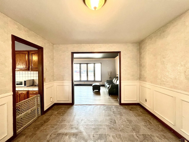 doorway to outside with a wainscoted wall and a decorative wall