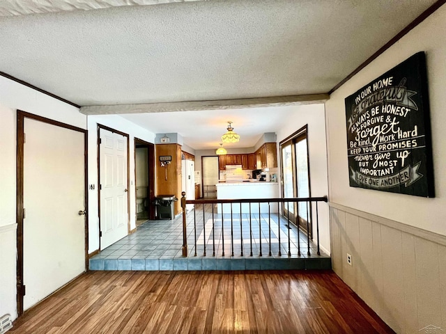 interior space with brown cabinetry, wainscoting, a textured ceiling, and wood finished floors