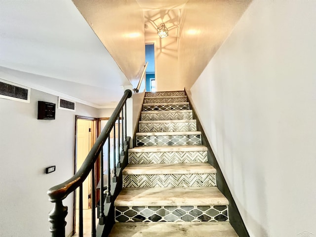 stairs with concrete floors, visible vents, crown molding, and baseboards