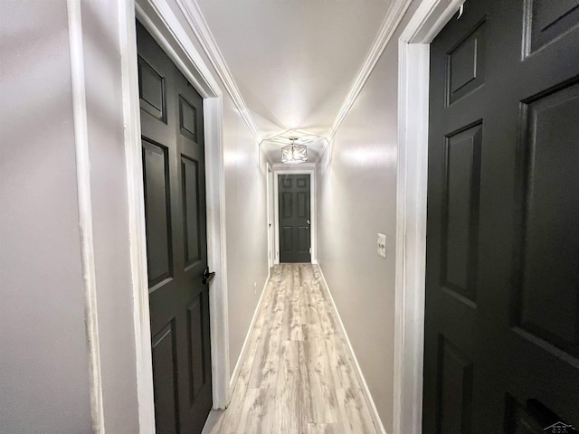 corridor with ornamental molding, baseboards, and light wood finished floors