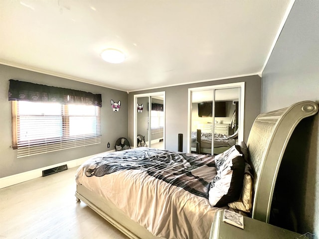 bedroom with ornamental molding, wood finished floors, visible vents, and baseboards