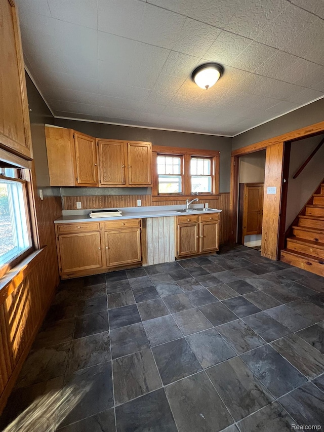 1517 Stanley St, Saginaw, MI 48602 - kitchen featuring wooden walls, light countertops, brown cabinets, wainscoting, and dark stone finish flooring