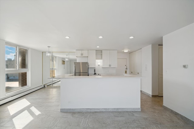 kitchen featuring recessed lighting, light countertops, freestanding refrigerator, white cabinetry, and a sink
