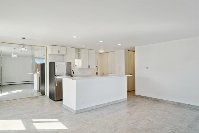 kitchen featuring baseboards, a kitchen island, freestanding refrigerator, baseboard heating, and white cabinetry