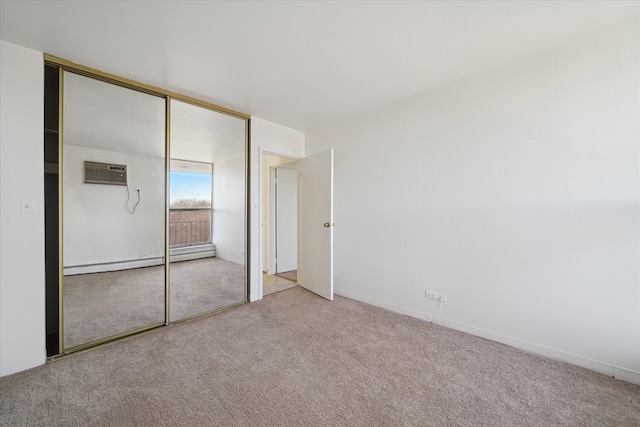 unfurnished bedroom featuring a baseboard radiator, baseboards, a closet, a wall mounted AC, and carpet