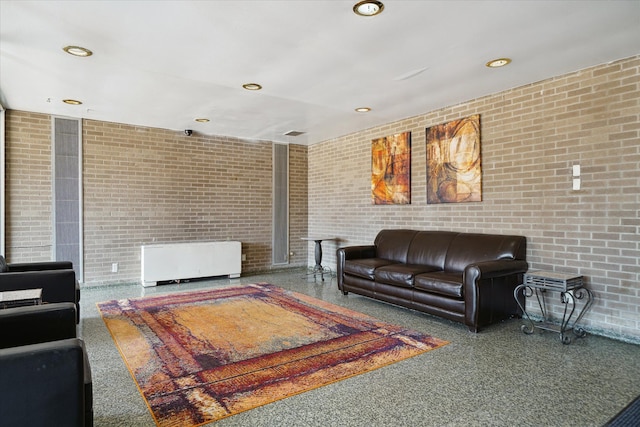 living area featuring brick wall, radiator heating unit, and recessed lighting