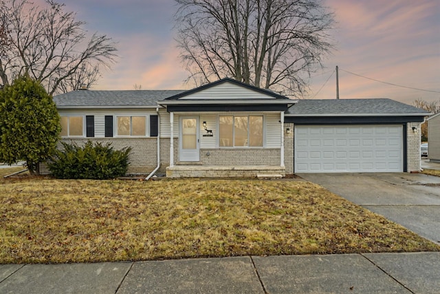 ranch-style home featuring a garage, driveway, brick siding, and a front yard