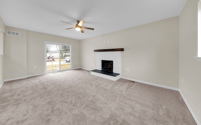 unfurnished living room with ceiling fan, a brick fireplace, carpet flooring, and visible vents