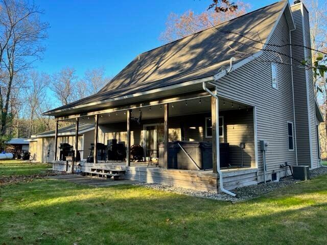 rear view of property featuring a yard, a chimney, and central air condition unit