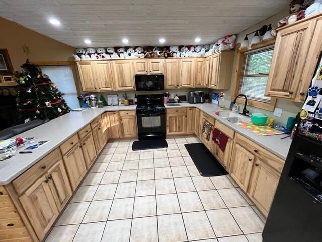 kitchen featuring light tile patterned floors, a sink, light countertops, light brown cabinetry, and black appliances